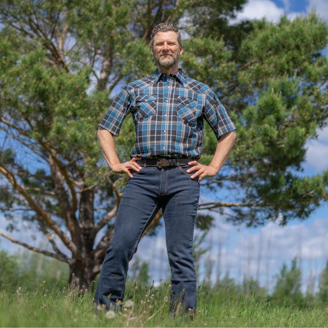Men's short-sleeve plaid western shirt. Western shirt is teal, black and white with pearl snaps.