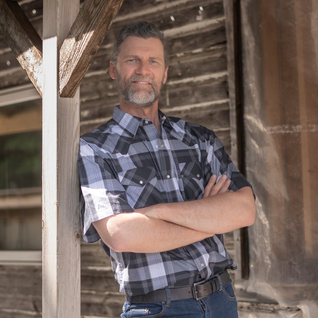 Men's short-sleeve plaid western shirt. Western shirt has pearl snaps and a dark plaid pattern.